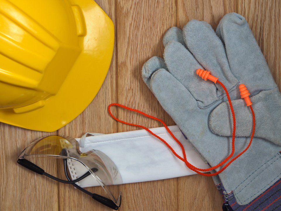 Casque, gants, lunettes de protection, bouchons d’oreilles et masque posés sur un plan de travail